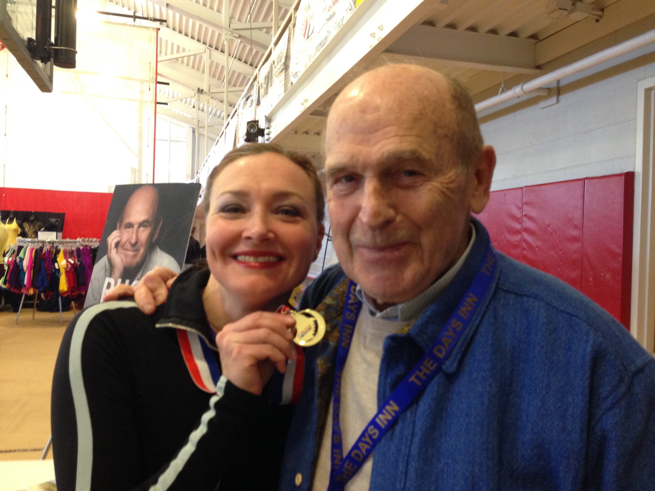 Allison holding a gold medal next to Dick Button, for the manleywoman skatecast, a figure skating podcast